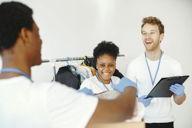 Happy volunteers organizing donated clothes, showing teamwork and collaboration in a community effort.